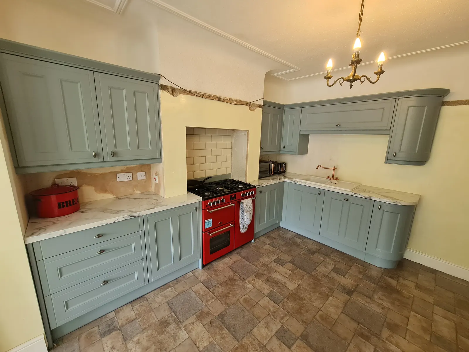Sage-coloured kitchen units in a completed renovation project